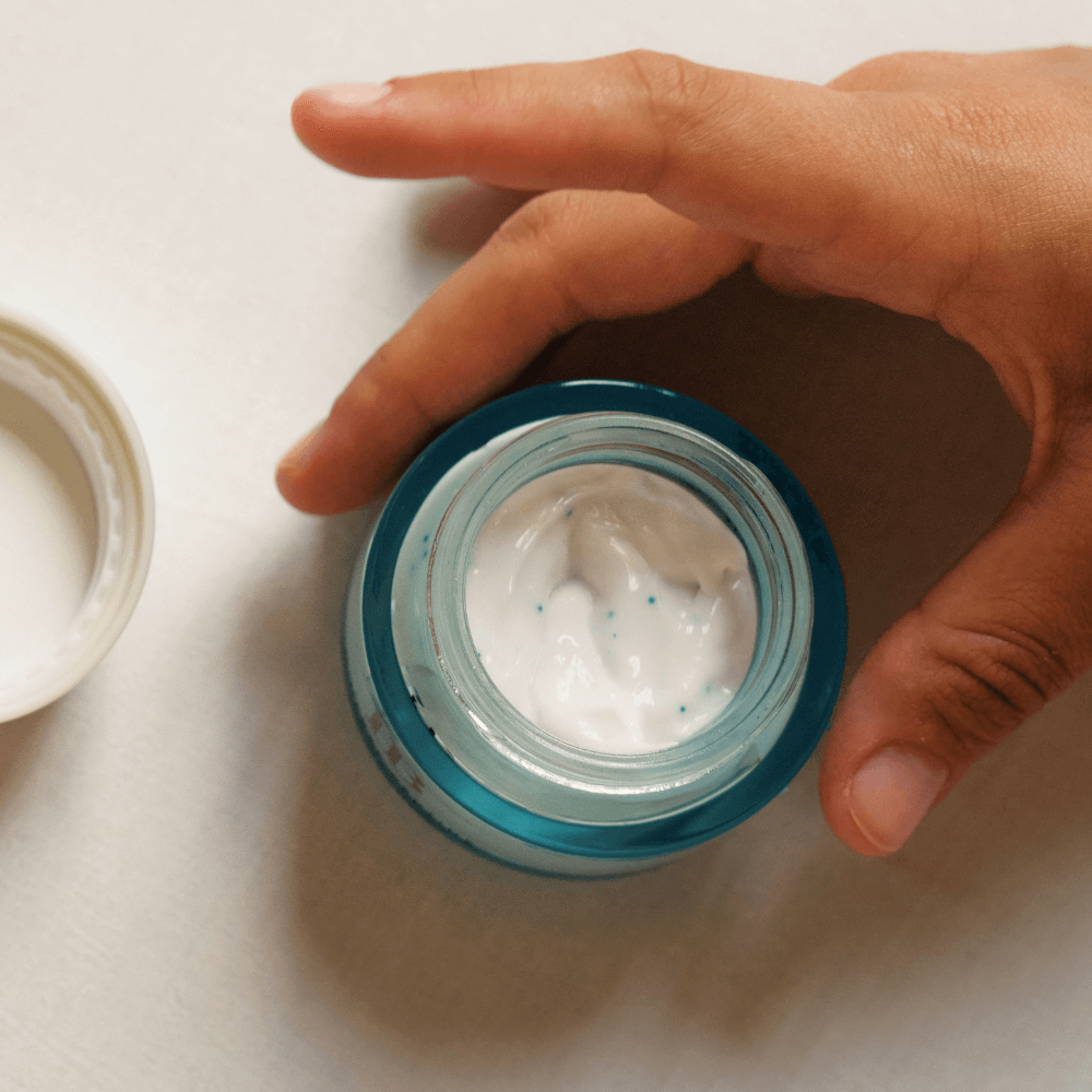 Hand holding a jar of cream with a white background