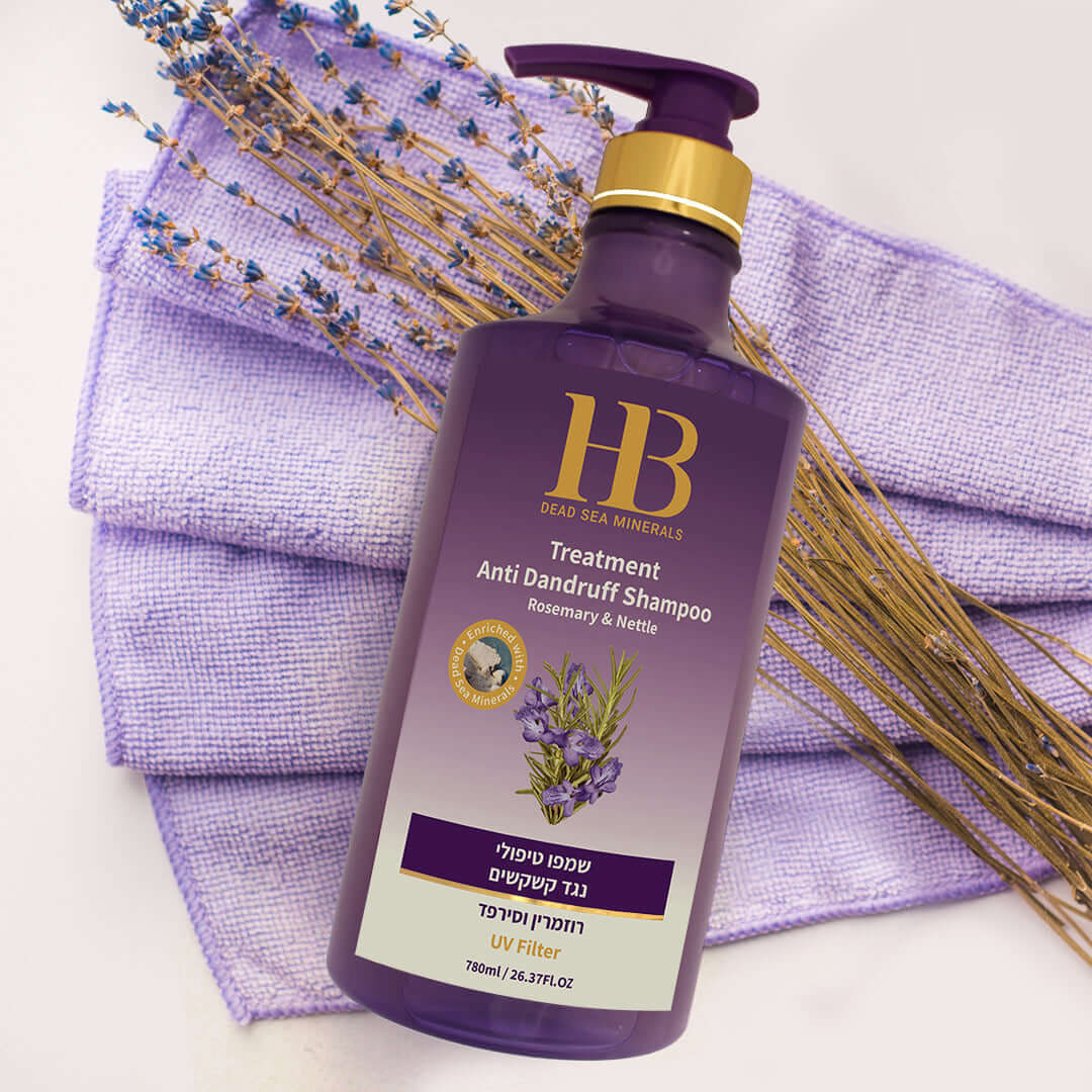 Purple shampoo bottle with gold pump on a purple towel with lavender and rosemary, featuring HB Dead Sea Minerals branding.